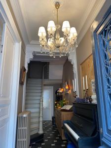 a hallway with a chandelier and stairs with a piano at Amato-Brugge in Bruges