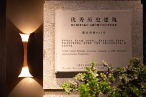 een bord voor een architectuurmonument naast een plant bij JingLai Bushe Hotel Bund Nanjing West Road Shanghai in Shanghai