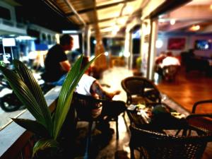 a man sitting at a table in a restaurant with a plant at Tiki Tribe Bar & Hostel in Ko Tao