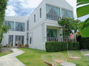 a white house with chairs in the yard at White Wall Riverfront Hotel in Kamphaeng Phet