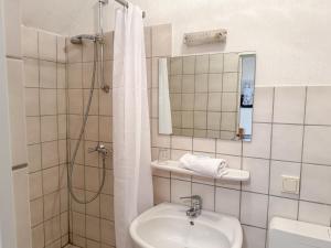 a bathroom with a sink and a shower with a mirror at Harzhotel Grünett in Langelsheim