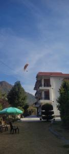 una cometa volando en el cielo sobre un edificio en Sunrise by Namastexplorer en Bhīm Tāl