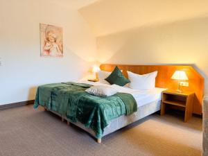 a hotel room with a bed with a green blanket at Harzhotel Grünett in Langelsheim