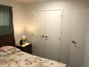 1 dormitorio con armario y 1 cama con colcha en Stand alone house - Pukekohe en Helvetia