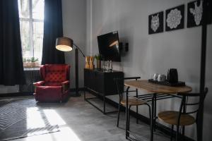 ein Wohnzimmer mit einem roten Stuhl und einem Tisch in der Unterkunft Apartament Kopalnia przy Zamkowej w Wałbrzychu in Wałbrzych