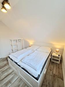 - une chambre avec un grand lit et des draps blancs dans l'établissement Ferienwohnung Seedune, à Fehmarn
