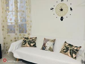 Golden Ambient Apartment في Chirivella: أريكة بيضاء في غرفة معيشة مع ساعة على الحائط