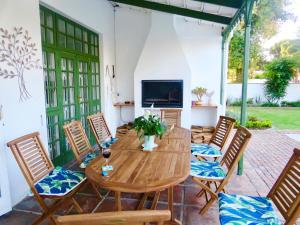 a patio with a wooden table and chairs at Whistlewood Guesthouse Walmer, Port Eizabeth in Port Elizabeth