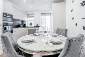 a white kitchen with a dining table and chairs at The Royal Sheperd in London