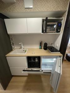 une petite cuisine avec un évier et un micro-ondes dans l'établissement Bmco cottage, à Estrées-Saint-Denis