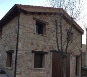 un edificio de piedra con tres ventanas y un árbol en Casa Rural El Retiro de los Casasola, en Establés