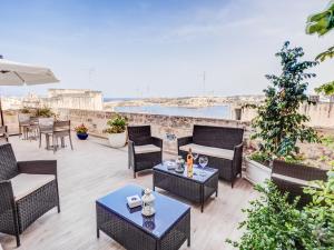 a patio with tables and chairs and a view of the ocean at Tano's Boutique Guesthouse in Valletta