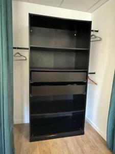un armario negro con estanterías vacías en una habitación en Appartement 3 pièces, en Saint-Paul-et-Valmalle