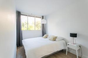 een witte slaapkamer met een bed en een raam bij Joli Duplex rénové à neuf de 72m² in Fresnes
