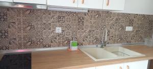 a kitchen with a sink and a tile wall at Anna -House Maria Manolaki, 2-Βedrm Apartment in Vourvourou