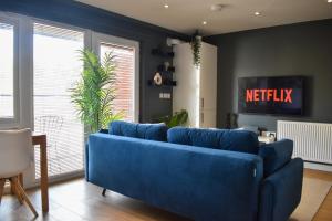 a blue couch in a living room with a tv at Stylish Peckham Apartment 10 Seconds From Station in London