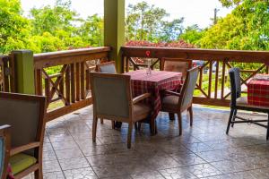 einen Tisch und Stühle auf einem Balkon mit einem Tisch und einem Glas in der Unterkunft Roxy's Mountain Lodge in Roseau