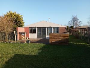 a house with a fence in a yard at Het andere huisje in Warmenhuizen