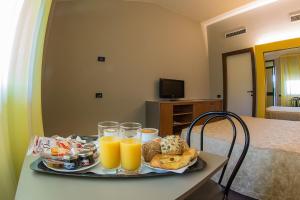 a tray of orange juice and bread on a table at Dealuna Motel in Fidenza