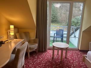 a hotel room with a table and chairs and a balcony at Waldhaus am See in Willingen