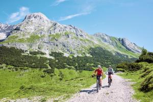 two people riding bikes down a dirt road in the mountains at Mountain Motel in Leutasch