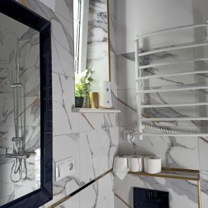 a bathroom with a mirror and white marble walls at tylko Sopot - 200m do plaży, Mariana Mokwy 4A in Sopot