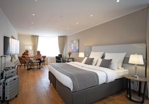 un dormitorio con una cama grande y personas sentadas en una habitación en Hotel Am Brinkerplatz, en Essen