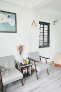 ein Wohnzimmer mit 2 Stühlen und einem Tisch in der Unterkunft Luti Homestay and Restaurant in Dong Hoi