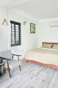 a white bedroom with a bed and a chair at Luti Homestay and Restaurant in Dong Hoi