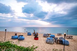 - une plage de sable avec des chaises et des tables dans l'établissement Le Méridien Phuket Mai Khao Beach Resort, à Mai Khao Beach