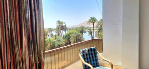 a chair on a balcony with a view of palm trees at Abo Hisham Nile Flat in Luxor