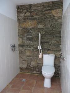 baño con aseo y pared de piedra en Obradoiro, en Sarria