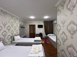 Habitación de hotel con 2 camas y TV en Aziz Hotel, en Samarkand