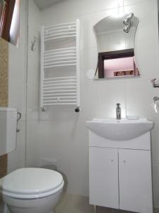 a white bathroom with a toilet and a sink at Vila Queen Mary in Constanţa
