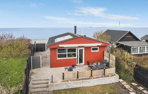 2 Bedroom Beach Front Home In Otterup في Otterup: منزل احمر صغير مع المحيط في الخلفية
