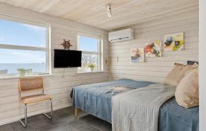 2 Bedroom Beach Front Home In Otterup في Otterup: غرفة نوم بسرير وتلفزيون وكرسي