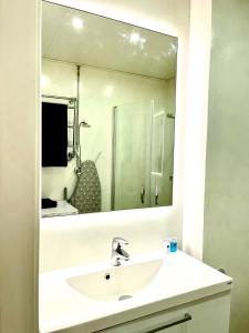ein Badezimmer mit einem Waschbecken und einem großen Spiegel in der Unterkunft Art Nouveau - Jugend Talo in Helsinki Center Apartment in Helsinki