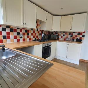 cocina con armarios blancos y fregadero de acero inoxidable en Beautiful and Cozy 2 Bedroom Apartment Billericay, en Billericay