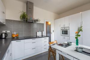 a white kitchen with white cabinets and a table at Maison Familiale proche sites JO 2024 in Nanterre