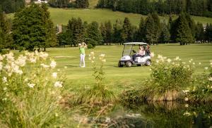 Um homem está a jogar golfe com um carrinho de golfe. em Pension Gertraud em Bad Kleinkirchheim
