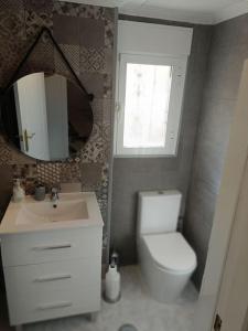 een badkamer met een toilet, een wastafel en een spiegel bij Chillax Villamartin in Alicante