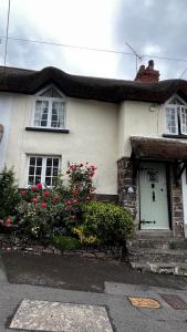 a white house with flowers in front of it at Cosy Nook in North Molton