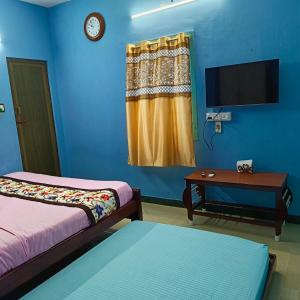 Habitación con 2 camas, TV y mesa. en Blue Waves HomeStay en Pondicherry