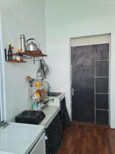 a kitchen with a stove and a black door at Rumah Pemandangan Lembah & Pegunungan tepi Jalan Raya in Banyumas
