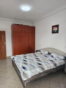 a bedroom with a bed and a wooden cabinet at Appartement de luxe in Cotonou