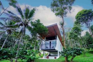 uma casa com varanda no meio das árvores em Crocolakes huts BY Travellikee em Kenichira