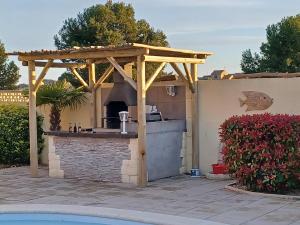 a wooden pergola with a kitchen in a backyard at Villa Manet Portiragnes in Portiragnes