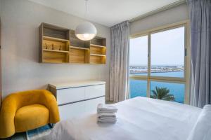 a bedroom with a bed and a chair and a window at Water surrounded beautiful 2BR apartment in Ras al Khaimah