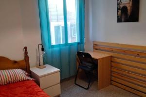 1 dormitorio con cama, escritorio y ventana en Apartamento Turístico Zaragoza en Zaragoza