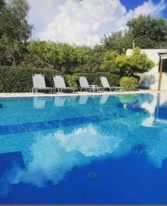 a swimming pool with chairs and blue water at Moulinos Studios in Svoronata